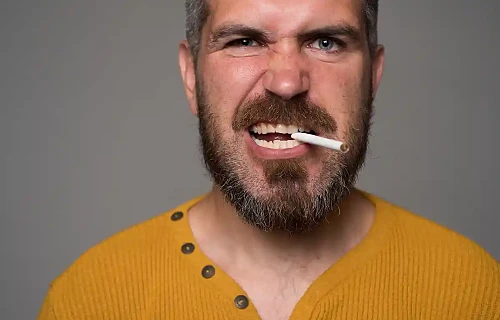 Piktos išraiškos barzdotas vyras, dantyse sukandęs cigaretę. Vaizdas simbolizuoja toksišką vyro elgesį, agresiją, sudėtingą charakterį ir raudonas vėliavas romantiniuose santykiuose.